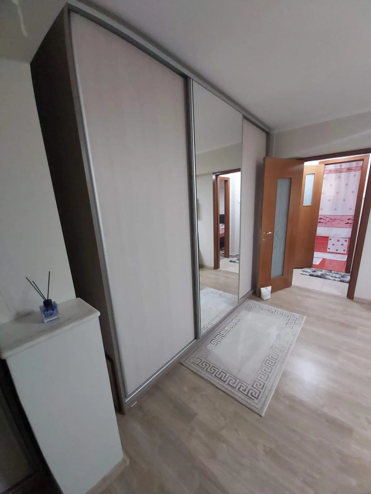 Dulapul de hol văzut din lateral, cu oglinda reflectând camera alăturată