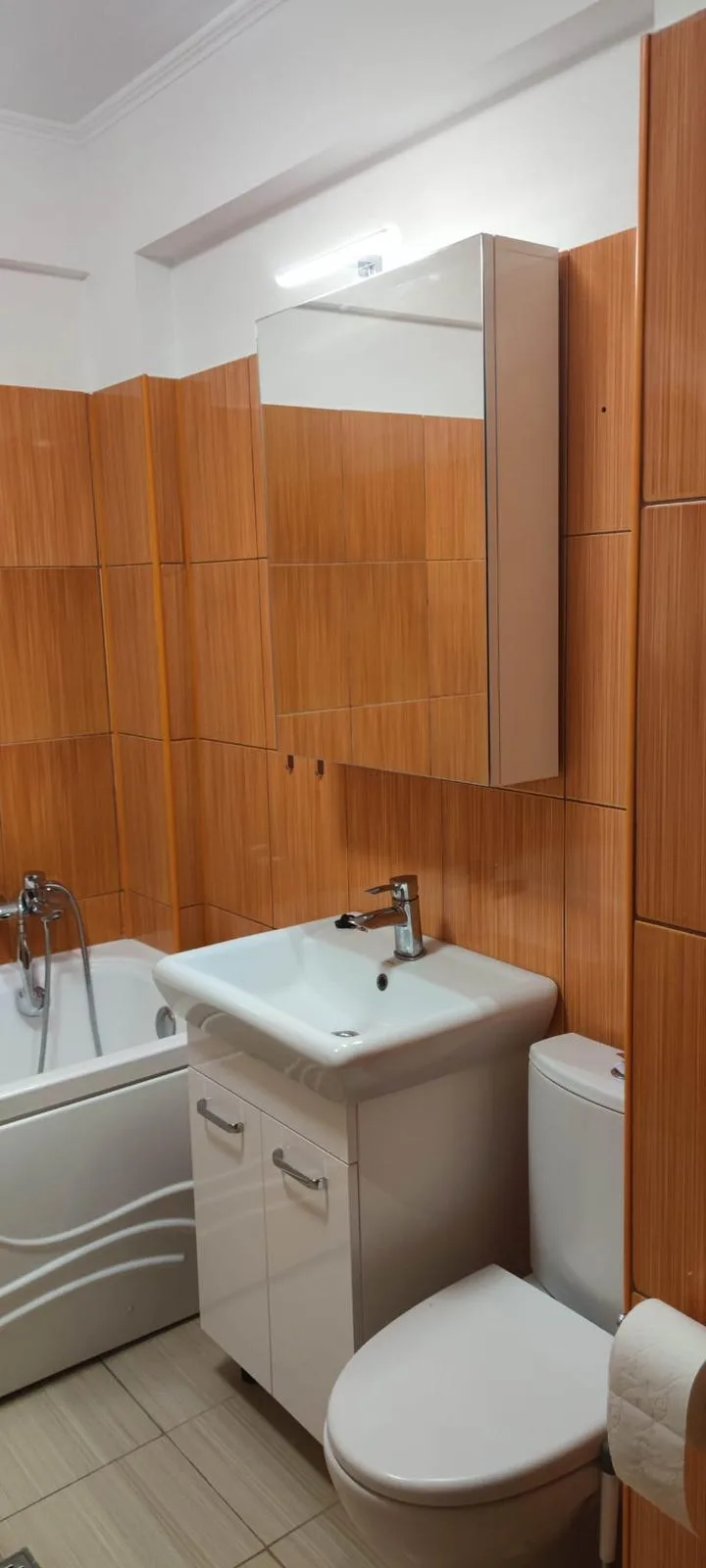 Baie mică cu faianță aspect lemn, mobilier alb lucios și dulap-oglindă cu LED
